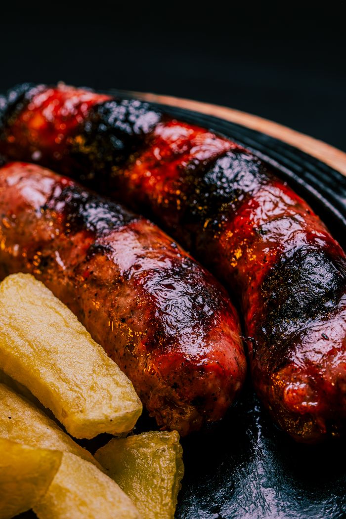 Close-up of grilled sausages and fried potatoes on a plate, perfect for a hearty meal.