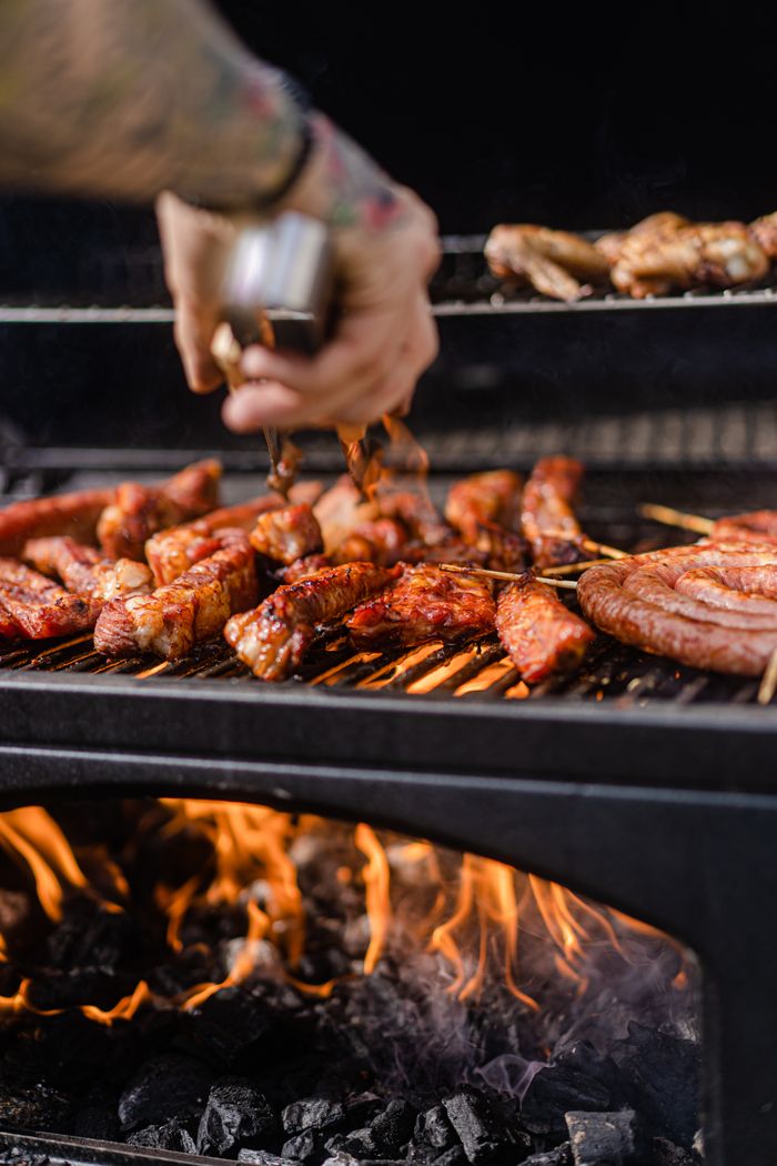 Grilling assorted meats over a flaming charcoal barbecue for a mouthwatering outdoor meal.